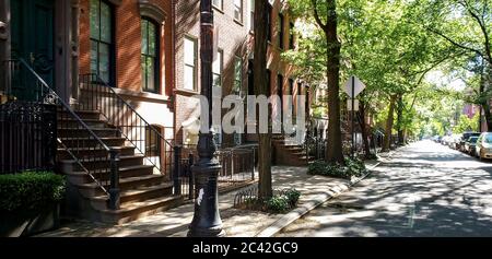 Sunlight shines on a block of historic brownstone buildings in the East Village neighborhood of Manhattan in New York City NYC Stock Photo