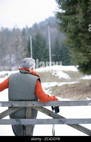 An old man with a remote throttle leans against a fence Stock Photo