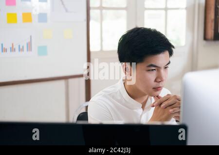Young finance market analyst working at office and analyze online marketing in his computer. Stock Photo
