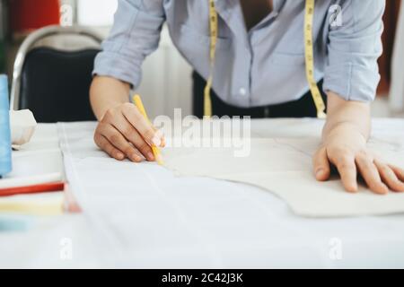 Closeup young  tailor working with sewing pattern drawing line on fabric with pencil chalk. Stock Photo