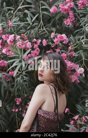 Portrait of young woman standing near oleander flower Stock Photo
