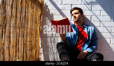Man reading a book on the balcony of his house. Reading at home concept. Stock Photo