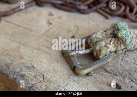 A very old buckle on a dog chain on top of a wooden table next to a rusted chain Stock Photo