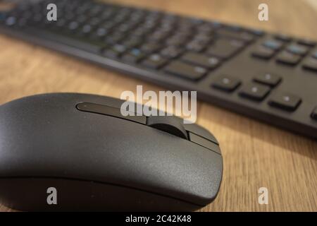Wireless mouse and keyboard set on top of a wooden office desk, on a workstation Stock Photo