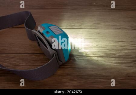 Teal headlamp turned on show the light beam on a wooden surface Stock Photo