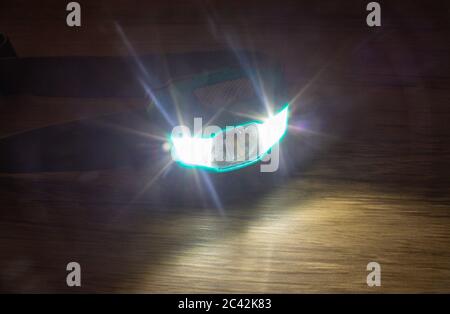 Teal headlamp turned on show the light bean on a wooden surface Stock Photo