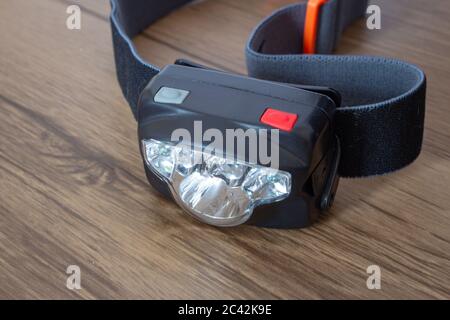 Black led headlamp turned off on a wooden table showing the elastic strap Stock Photo