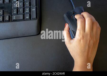 Closeup on the hand of a woman using her computer, with a keyboard and a mouse Stock Photo