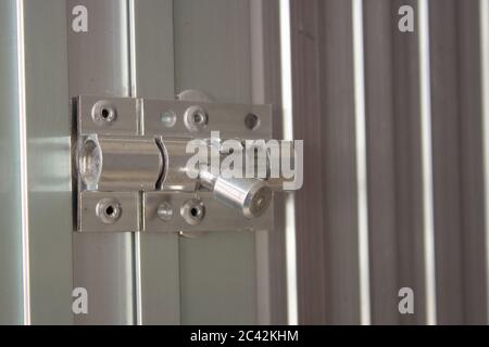 Aluminum latch on an aluminum door frame, brand new and shiny Stock Photo