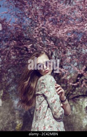 Portrait of a young woman standing near spring blossom tree Stock Photo