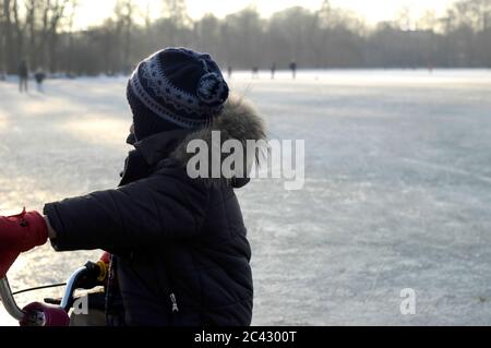 Child rides a bicycle in a winter landscape - cold - leisure Stock Photo