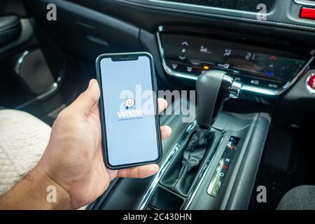 A man holding the iPhone X with Waze navigation app inside the car. Waze has gain popularity for its good navigation. Stock Photo