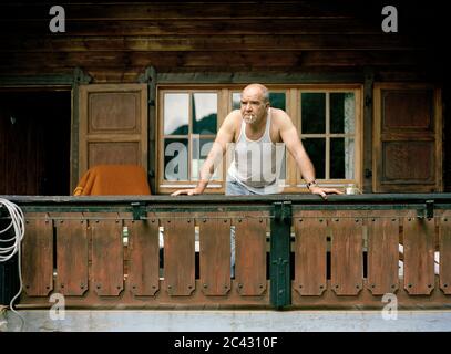 Old man stands on the balcony and looks down Stock Photo