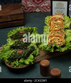 Green herbal omlette on a lettuce leaf on a wooden board served with roll salad Stock Photo