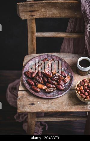 Dried dates on a ceramic plate on a rustic wooden chair Stock Photo