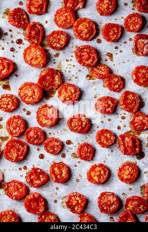 Sun-dried cherry tomatoes with olive oil and balsamic vinegar on baking paper. Top view, food background Stock Photo