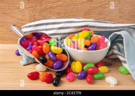 a baker's scoop of colorful jelly beans and a small dish of jelly beans on a wooden table Stock Photo