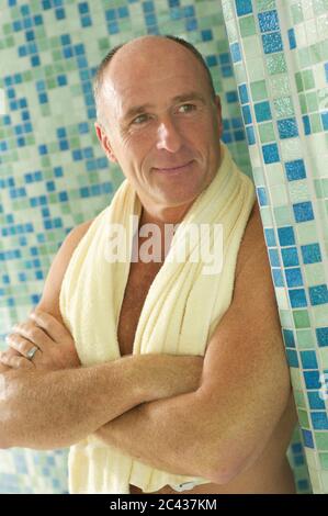 Elderly man is standing in the bathroom, towel around neck Stock Photo