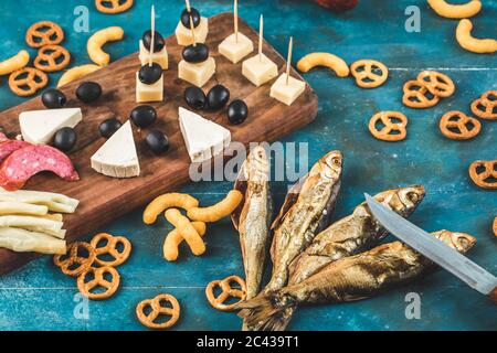 Sausage slices with cheese cubes, olives and crackers with dry fish on the blue table Stock Photo