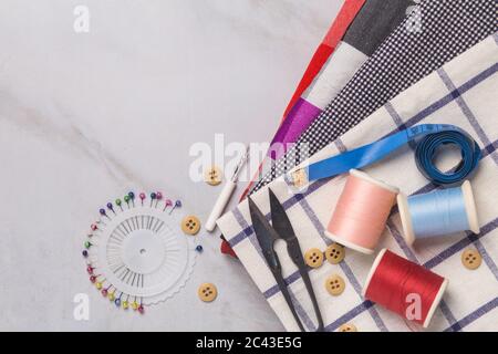 sewing tools : the fabric, scissors, pins, tape measure, threads on tailor desk, top view Stock Photo
