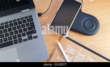 Mobile phone and smart watch on a dual wireless charger with a tablet and a stylus concept for wireless technology and portable information devices Stock Photo