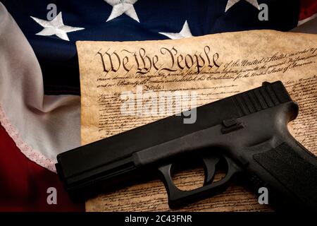 The second amendment and gun control in america concept with a handgun and the american constitution on the USA flag with close up on the 'we the peop Stock Photo
