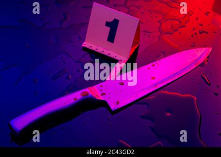 Forensic science, murder weapon and criminal investigation concept theme with kitchen knife covered in blood next to numbered marker in a dark bloody Stock Photo