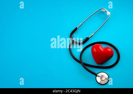 Yearly health check up, disease diagnosis medicine, healthcare and cardiology concept with a red heart and a stethoscope isolated on a hospital blue b Stock Photo