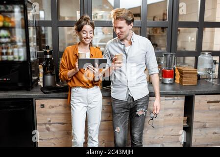 Two young managers or shop owners having some discussion in the shop or cafe. Small business management concept Stock Photo