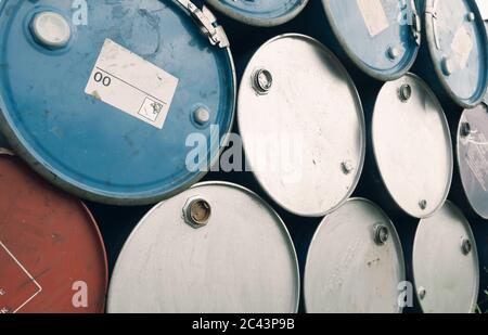 Old chemical barrels. Blue and purple oil drum. Steel oil tank. Toxic waste warehouse. Hazard chemical barrel with warning label. Industrial waste. Stock Photo