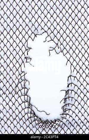 The hole in the steel mesh covered with snow Stock Photo