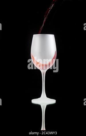 Red wine in modern white tall glass on black background with reflection Stock Photo