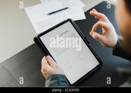 Man reading stock purchase agreement on tablet and showing ok gesture. Stock Photo