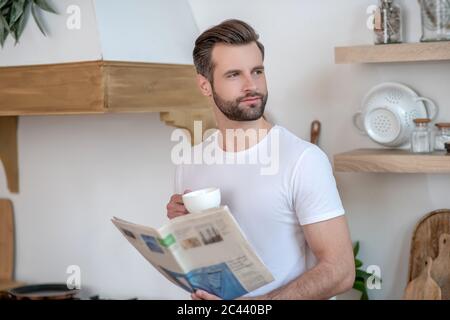 Dark-haired handsome man holding a newspaper aand having coffee Stock Photo