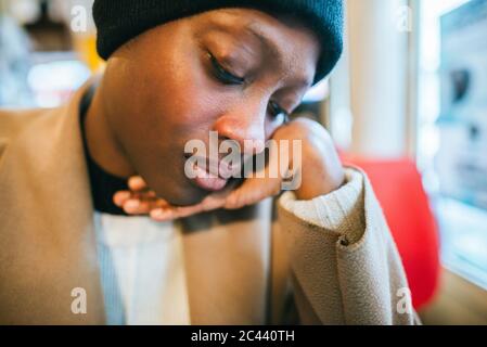 Pensive young woman with hand on chin in coffee shop Stock Photo