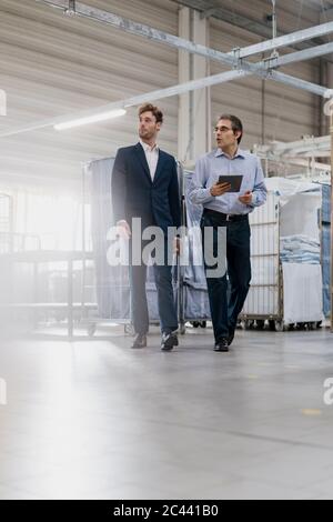 Two businessmen with tablet having a meeting in a laundry shop Stock Photo