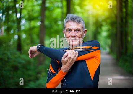 Portrait of confident elderly active man stretching at park Stock Photo