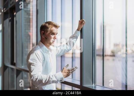 Businessman doing a call with a headset, standing at the window Stock Photo