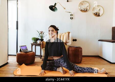 Smiling young woman practicing yoga at home Stock Photo