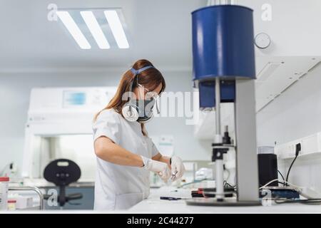 Confident female scientist doing medical research at desk in laboratory Stock Photo