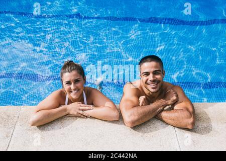 Smiling young couple standing in swimming pool Stock Photo