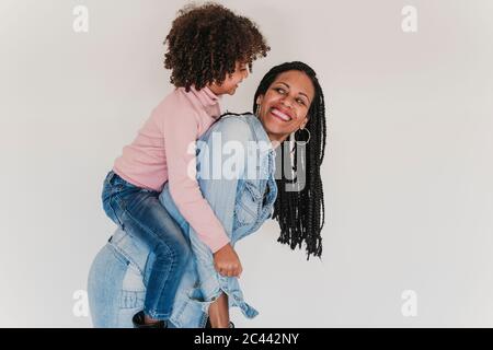 Portrait of happy mother giving her little daughter a piggyback ride Stock Photo