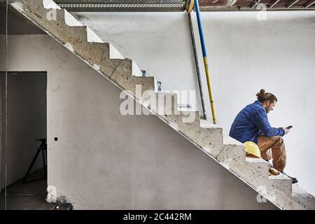 Construction worker using smartphone at construction site Stock Photo