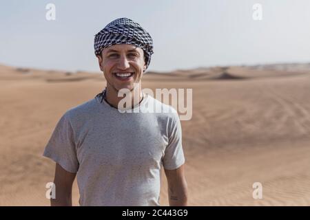 Happy young man standing at desert in Dubai, United Arab Emirates Stock Photo