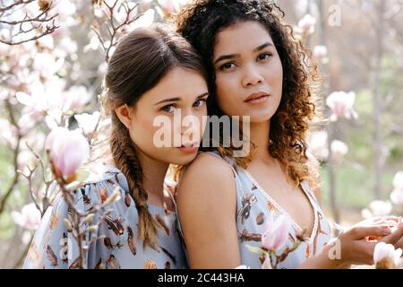 Affectionate twin sisters standing in a sunny field Stock Photo - Alamy