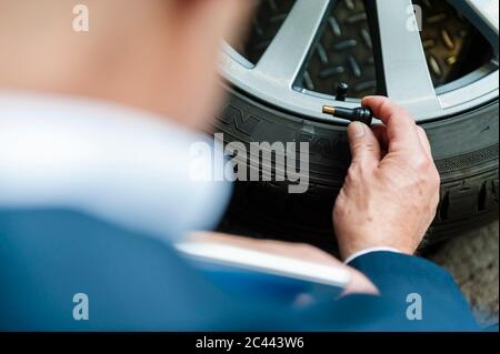 Senior businessman holding air valve by tire at store Stock Photo