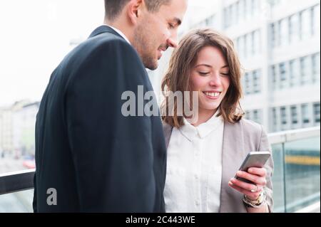 Business couple using smart phone outside office building Stock Photo