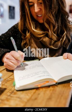 Woman writing in notebook in coffee shop Stock Photo