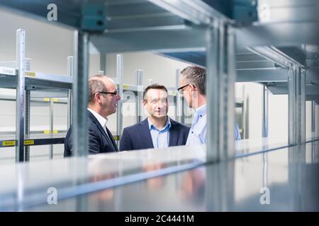 Three businessmen having a discussion in a factory storehouse Stock Photo