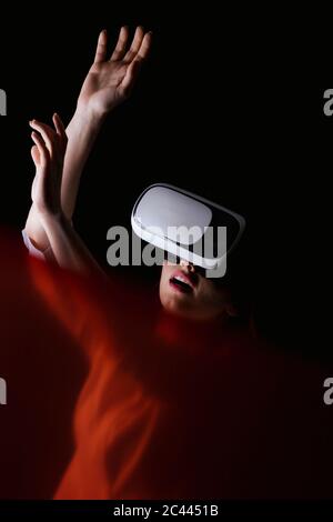 Young woman using VR glasses over black background Stock Photo